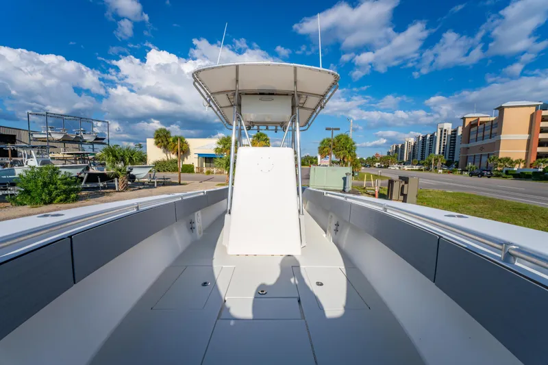 Slide: The Image of 1997 Contender 27 boat with T-top, parked near buildings under a blue sky. - 23