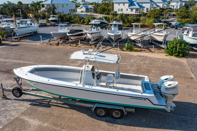 Slide: The Image of 1997 Contender 27 boat with Suzuki engines on a trailer in a marina. - 30