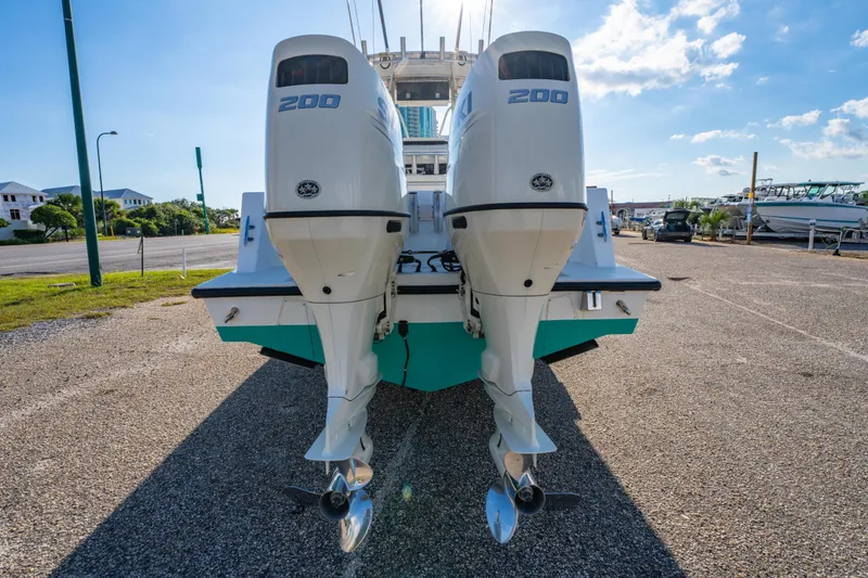 Slide: The Image of 1997 Contender 27 boat with twin 200 horsepower outboard engines, parked on gravel. - 4