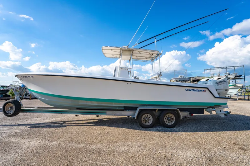 Slide: The Image of 1997 Contender 27 boat on trailer under clear blue sky. - 6