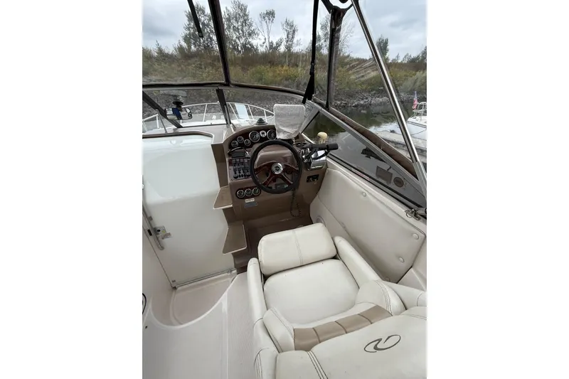 Slide: The Image of 2004 Regal Commodore 2765 boat cockpit with steering wheel and controls, docked near trees. - 4