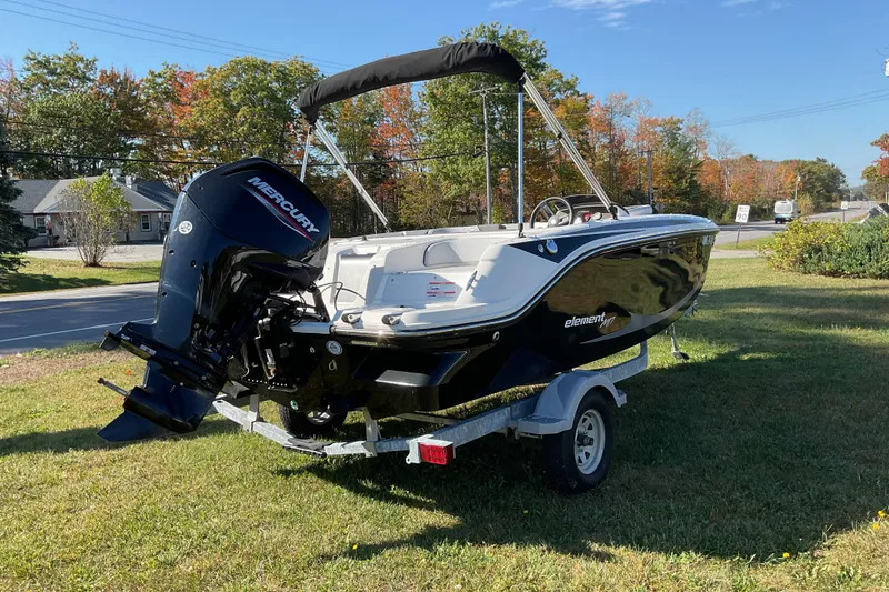 Slide: The Image of 2022 Bayliner Element M17 boat on trailer, parked on grass with trees in background. - 8