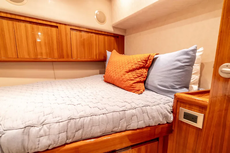 Slide: The Image of Cozy cabin interior of 2014 Viking 46 Convertible yacht with wooden accents and plush bedding. - 30