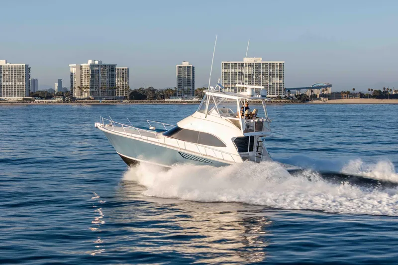 Slide: The Image of 2014 Viking 46 Convertible yacht cruising near coastal city skyline. - 8