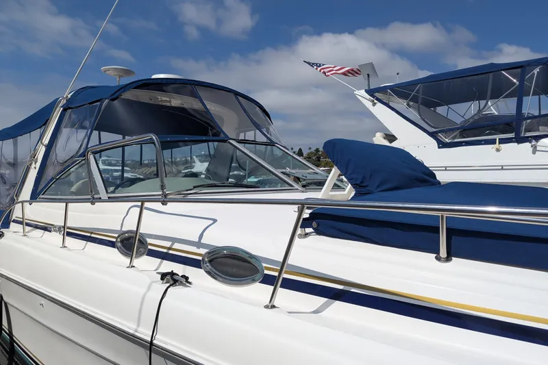 Slide: The Image of 2001 Sea Ray 340 Sundancer boat docked, featuring blue canopy and American flag. - 19