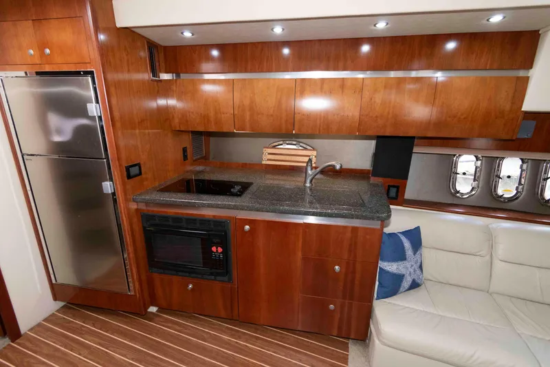 Slide: The Image of Luxurious 2007 Cruisers Yachts 420 Express interior kitchen with wood cabinetry and modern appliances. - 12