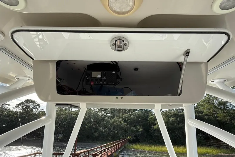 Slide: The Image of 2015 Sportsman Masters 247 Bay Boat electronics compartment with open hatch, showing interior equipment. - 14