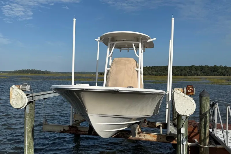 Slide: The Image of 2015 Sportsman Masters 247 Bay Boat on lift by the water, clear sky background. - 3