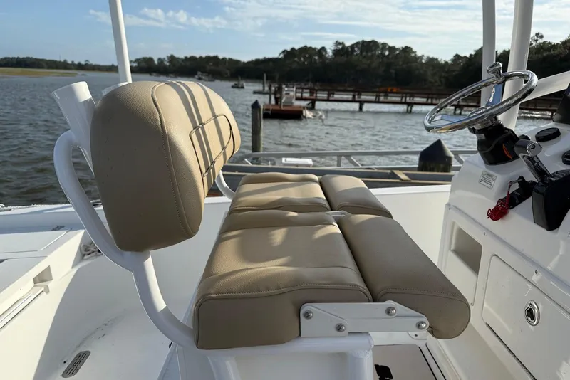 Slide: The Image of 2015 Sportsman Masters 247 Bay Boat interior with beige seating and steering wheel, dockside view. - 4