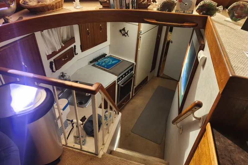 Slide: The Image of Interior of a 1977 Post Sport Fish boat, featuring a compact kitchen and wooden accents. - 17