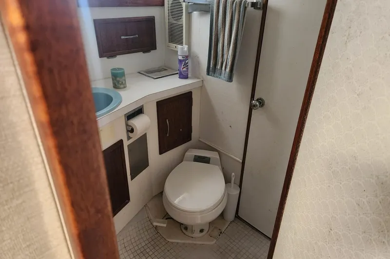 Slide: The Image of 1977 Post Sport Fish boat bathroom with toilet, sink, and storage cabinets. - 19