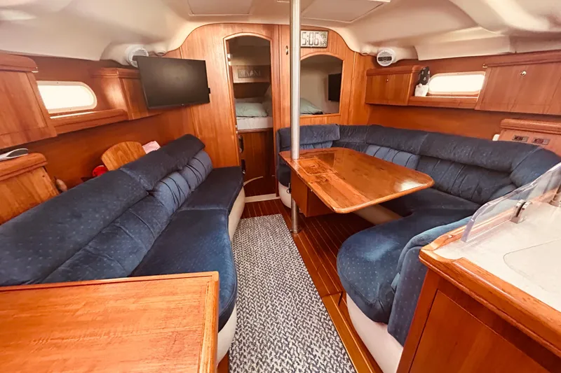 Slide: The Image of Interior of 2003 Hunter 386 sailboat with blue seating and wooden table. - 14