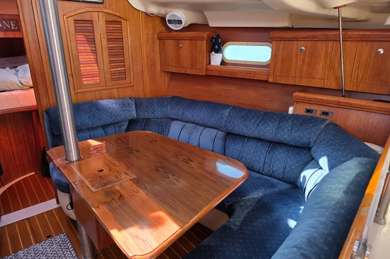 Slide: The Image of Interior of a 2003 Hunter 386 sailboat with wooden cabinetry and blue cushioned seating. - 15