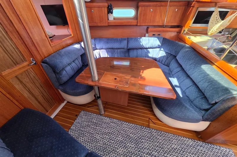Slide: The Image of Cozy interior of 2003 Hunter 386 sailboat with blue cushioned seating and wooden table. - 16