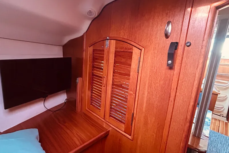 Slide: The Image of Interior of 2003 Hunter 386 sailboat with wooden cabinetry and mounted TV. - 33