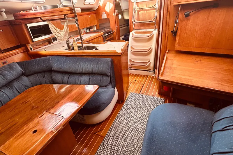 Slide: The Image of Interior of a 2003 Hunter 386 sailboat with wooden furnishings and blue seating. - 35