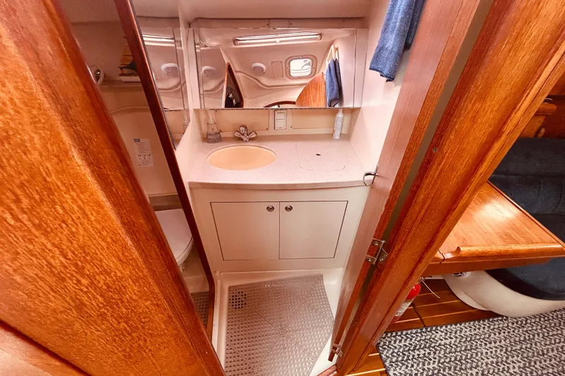 Slide: The Image of Compact bathroom in a 2003 Hunter 386 sailboat with wooden accents and a small sink. - 38