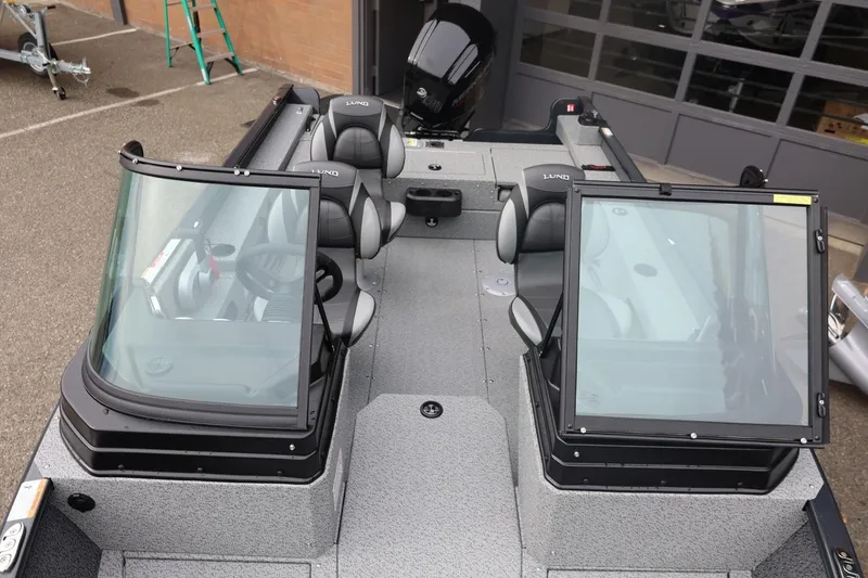 Slide: The Image of 2026 Lund 1775 Adventure Sport boat interior with seating and windshield, parked outdoors. - 43