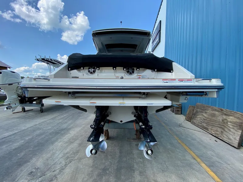 Slide: The Image of 2019 Sea Ray 310 SLX boat, rear view, docked beside a blue building under a clear sky. - 4