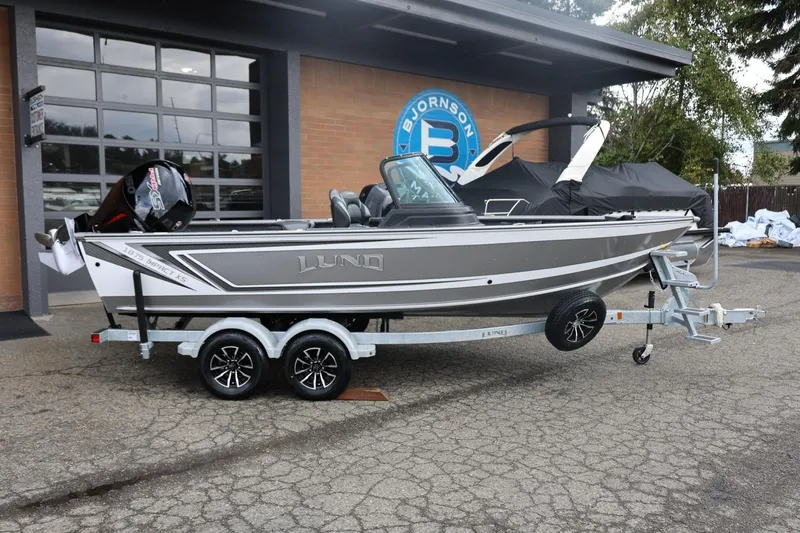 Slide: The Image of 2026 Lund 1875 Impact XS Sport boat on trailer, parked outside a building. - 1