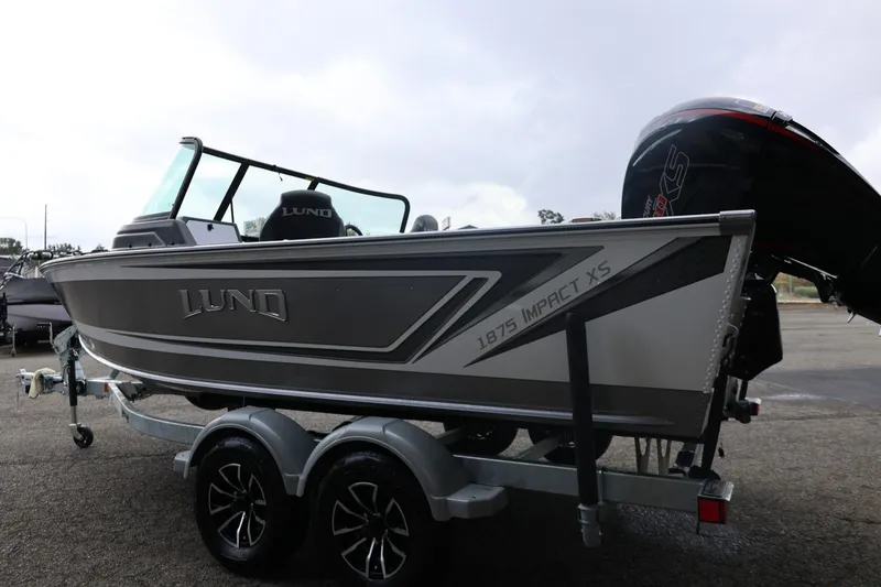 Slide: The Image of 2026 Lund 1875 Impact XS Sport boat on trailer, side view, overcast sky. - 10
