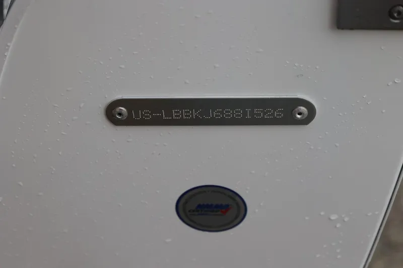 Slide: The Image of 2026 Lund 1875 Impact XS Sport boat identification plate with water droplets. - 17