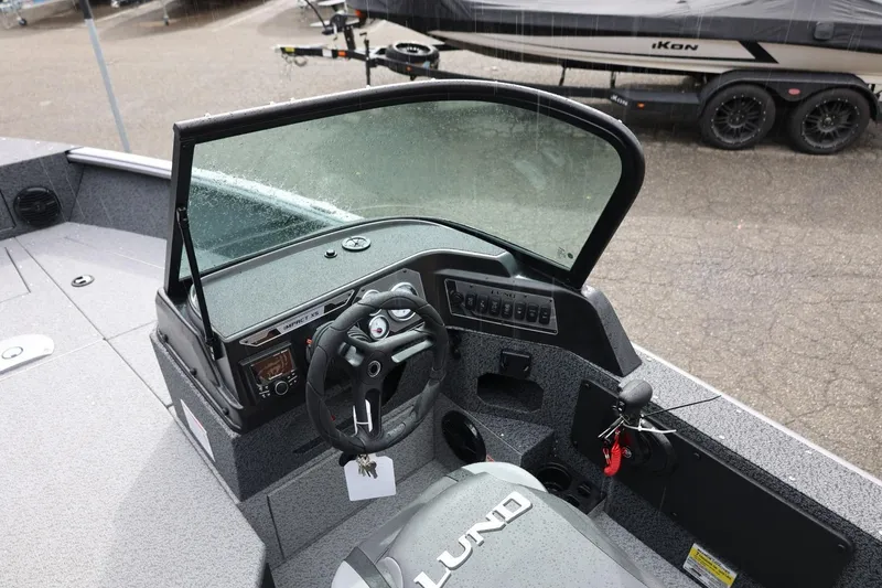 Slide: The Image of 2026 Lund 1875 Impact XS Sport boat interior with steering wheel and dashboard controls. - 33