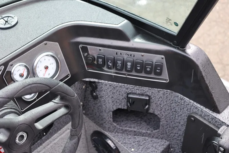 Slide: The Image of 2026 Lund 1875 Impact XS Sport boat dashboard with steering wheel and control panel. - 34