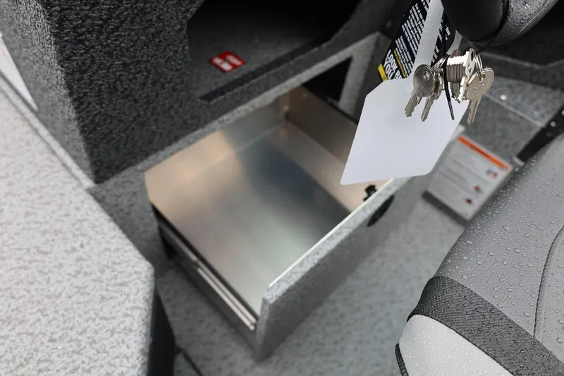 Slide: The Image of 2026 Lund 1875 Impact XS Sport boat interior with open storage compartment and keys. - 42