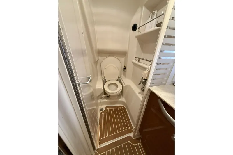 Slide: The Image of 2009 Sea Ray 350 Sundancer bathroom with toilet, shelves, and wooden floor accents. - 18
