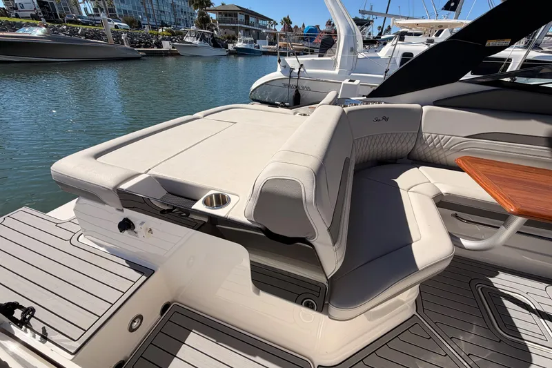 Slide: The Image of 2024 Sea Ray SLX 260 boat interior with luxurious seating and wooden table in a marina setting. - 13