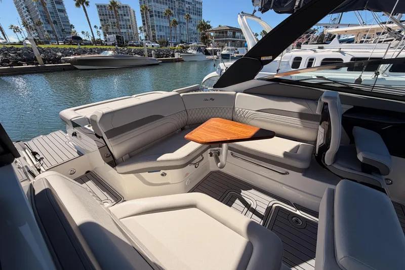 Slide: The Image of 2024 Sea Ray SLX 260 boat interior with luxurious seating and wooden table, docked in marina. - 14