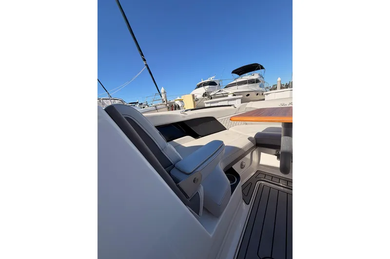 Slide: The Image of 2024 Sea Ray SLX 260 boat interior with seating and table, docked under clear blue sky. - 35