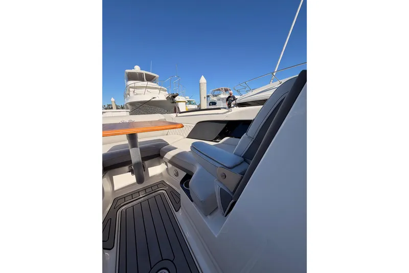 Slide: The Image of 2024 Sea Ray SLX 260 boat interior with seating and table, docked under clear blue sky. - 36