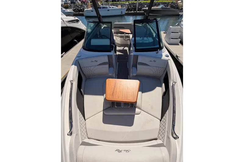 Slide: The Image of 2024 Sea Ray SLX 260 boat interior with seating and wooden table, docked at marina. - 37