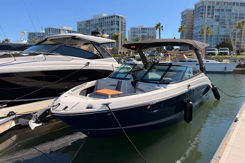 Slide: The Image of 2024 Sea Ray SLX 260 boat docked in marina, surrounded by modern buildings. - 4