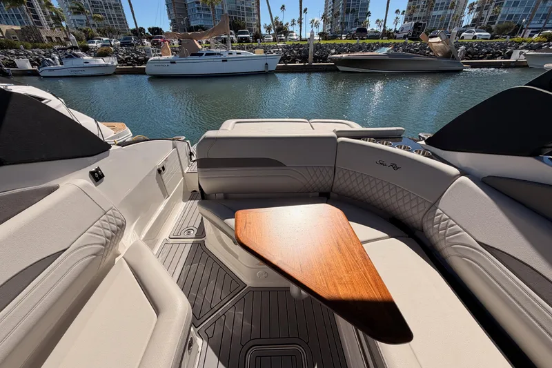 Slide: The Image of 2024 Sea Ray SLX 260 boat interior with elegant seating and wooden table, docked in marina. - 40