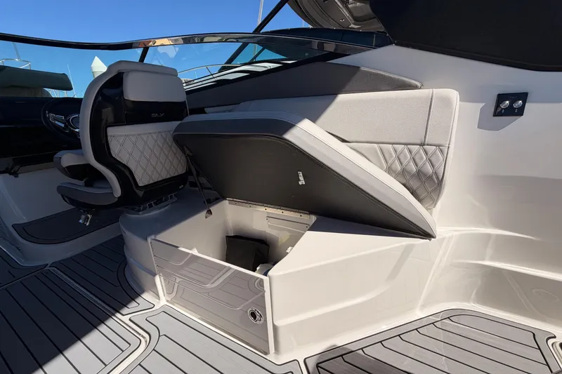 Slide: The Image of 2024 Sea Ray SLX 260 boat interior with open storage compartment and luxury seating. - 53