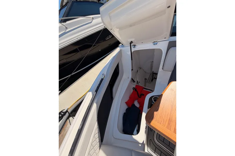 Slide: The Image of 2024 Sea Ray SLX 260 boat storage compartment with life jackets and wooden table. - 56
