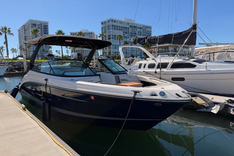 Slide: The Image of 2024 Sea Ray SLX 260 boat docked at marina with modern buildings in background. - 6