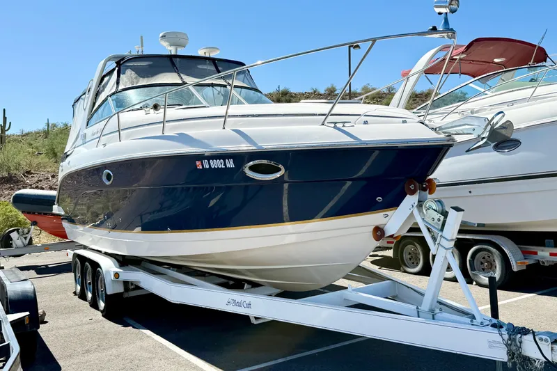 The Image of 2005 Rinker Fiesta Vee 300 boat on trailer, parked outdoors under clear sky. - 1