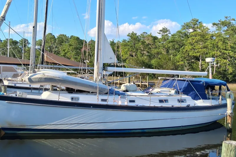 The Image of 1978 Pearson 424 sailboat docked, surrounded by trees and clear blue sky. - 0