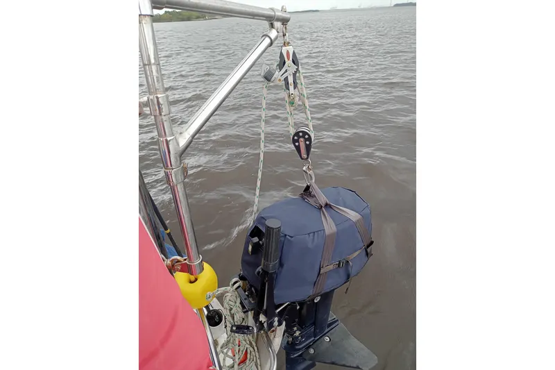 Slide: The Image of Sailboat equipment on Pearson 424, 1978 model, with hoisted outboard motor over water. - 13