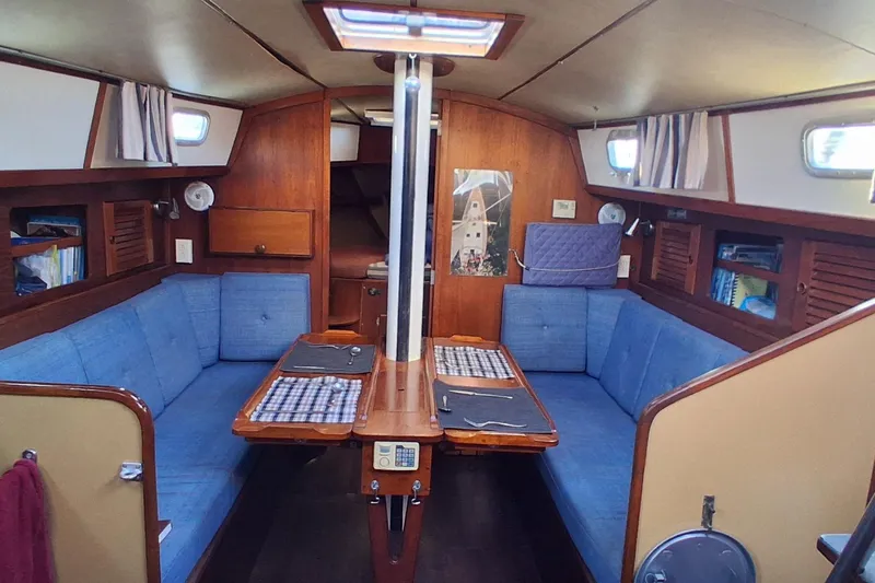 Slide: The Image of 1978 Pearson 424 sailboat interior with blue seating, wooden table, and nautical decor. - 19