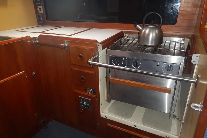 Slide: The Image of 1978 Pearson 424 yacht galley with stove, kettle, and wooden cabinetry. - 21