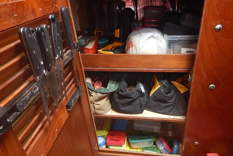 Slide: The Image of Storage area inside a 1978 Pearson 424 sailboat, featuring knives and organized tools. - 26