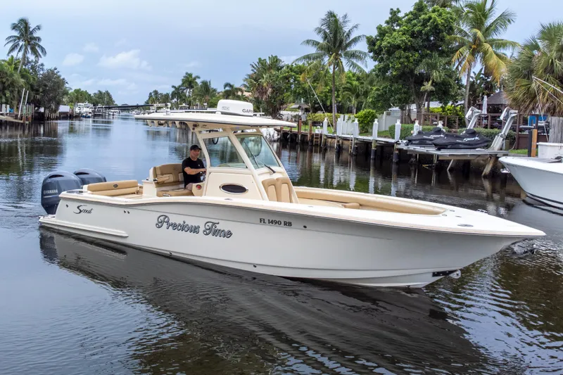 Slide: The Image of 2015 Scout 275 LXF boat cruising on a scenic waterway with palm trees. - 14