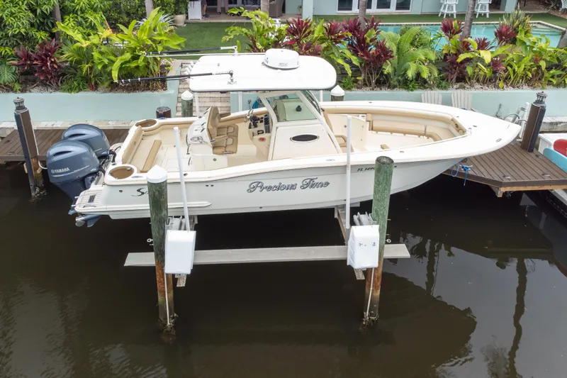 Slide: The Image of 2015 Scout 275 LXF boat docked with dual Yamaha engines, surrounded by lush greenery. - 23