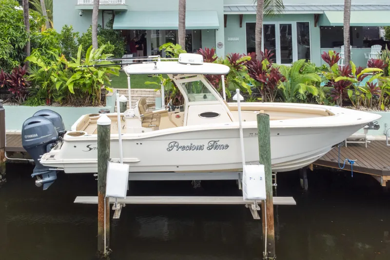Slide: The Image of 2015 Scout 275 LXF boat docked near tropical plants and waterfront home. - 24