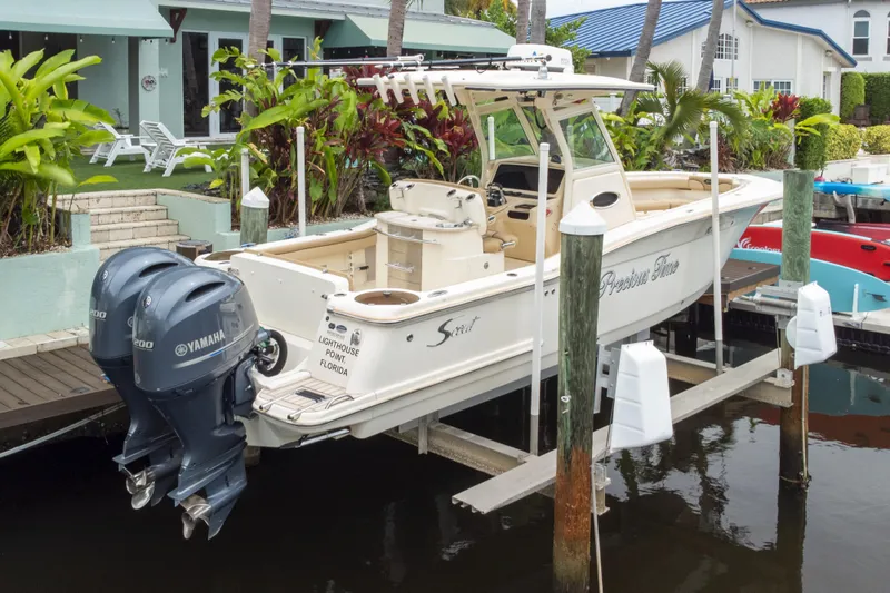 Slide: The Image of 2015 Scout 275 LXF boat docked with twin Yamaha engines in a scenic waterfront setting. - 25